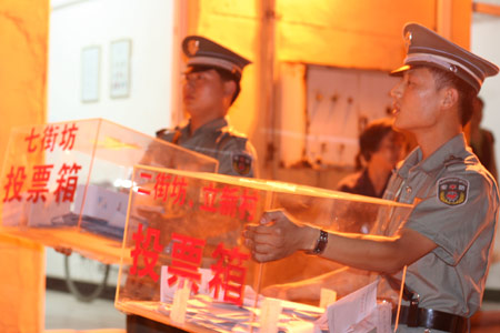 Two security men carry balloting boxes to a counting center after a voting on the housing demolition and compensation policy at Jiuxianqiao sub-district in Chaoyang District of Beijing, June 9, 2007. Some 3,711 families, about 57% of the 5,473 families, cast their votes on Saturday, with 2,451 votes for and 1,228 votes against the demolition and compensation plan. Thirty-two votes were invalid.