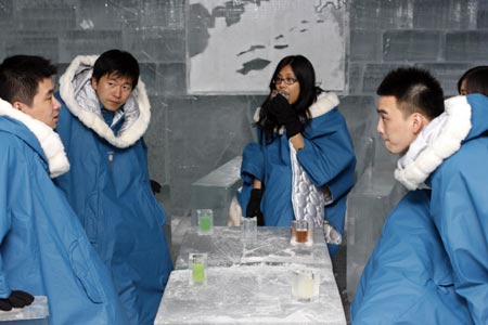 Customers chat and drink as they visit the Absolut Ice bar in Shanghai July 5, 2007. Workers carved out all the interior fittings, furniture and artworks of the Ice bar from a 40-ton ice block, which was transported to Shanghai from the Torne River in northern Sweden, according to local media. 