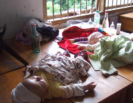 Babies lie on desks at a school in Southwest China's Chongqing Municipality, July 18, 2007. Residents were evacuated into a school after flood submerged low-lying areas in Chongqing.[Lu Wenwen]