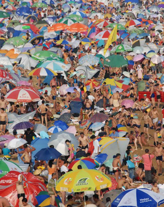 Vacationers gather by the sea at Fujiazhuang Beach in Dalian, Northeast China's Liaoning Province, July 28, 2007. The temperature reached 34.5 degrees Celsius on Saturday, pushing more people to beaches to escape the hot weather. [newsphoto]
