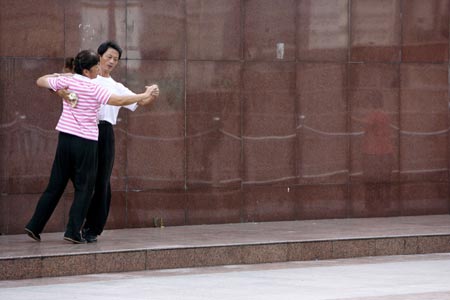 A couple dances at the Bund on the banks of the Huangpu River in Shanghai August 6, 2007. The Bund is one of the most famous tourist sites in Shanghai. Locals use the Bund as a place for morning exercises as well as other activities.