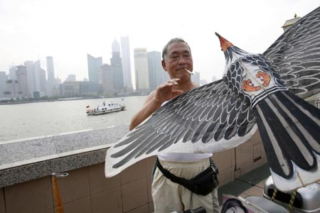 A man packs up his kite after playing with it at the Bund on the banks of the Huangpu River in Shanghai August 6, 2007. The Bund is one of the most famous tourist sites in Shanghai. Locals use the Bund as a place for morning exercises as well as other activities. 