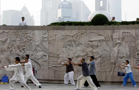 Locals practise tai chi at the Bund on the banks of the Huangpu River in Shanghai August 6, 2007. The Bund is one of the most famous tourist sites in Shanghai. Locals use the Bund as a place for morning exercises as well as other activities.