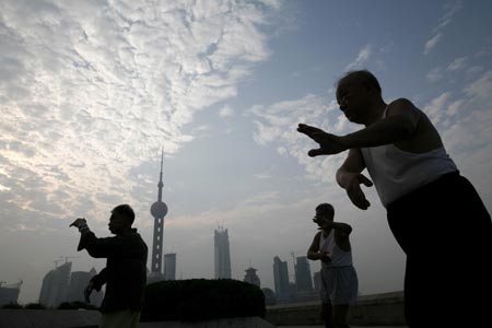 Locals practise tai chi at the Bund on the banks of the Huangpu River in Shanghai August 6, 2007. The Bund is one of the most famous tourist sites in Shanghai. Locals use the Bund as a place for morning exercises as well as other activities.