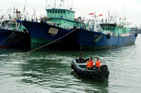 Chinese soldiers inspect the ships anchored at the Dongshan Harbour before the tropical storm Wutip hits the coastal areas in East China’s Fujian Province August 9, 2007. Wutip, meaning 'butterfly', is set to unleash gales and rain in Fujian and neighboring Zhejiang province from late Thursday through to Friday, Xinhua News Agency reported. [Xinhua]