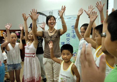 A teacher (C) leads a group of students to practice sign language at a library in Nanjing, East China's Jiangsu Province, August 14, 2007. The training class, organized by the library, aims to improve communication between normal children and those who are deaf or mute. [Xinhua]