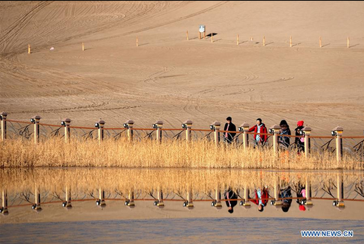 Tourists visit crescent spring of Mingsha Hill in Dunhuang