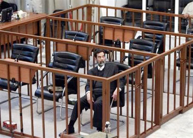 Former Iraqi President Saddam Hussien sits alone in the defendant's cage during cross-examination at his trial held in Baghdad's heavily fortified Green Zone, Wednesday April 5, 2006. Saddam Hussein was cross-examined for the first time in his six-month-old trial Wednesday, saying he approved death sentences against Shiites in the 1980s because he believed the evidence had proven they were involved in an assassination attempt against him. (AP 