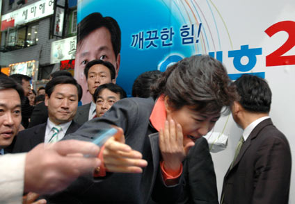 An unidentified man, whose hand is seen on left in this photo, uses a penknife to assault Park Geun-hye, leader of South Korea's main opposition Grand National Party during a campaign for local elections in Seoul May 20, 2006. Park suffered a 10-cm cut on the right side of her face after the assault, local media reported. 