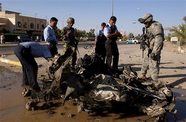A U.S. soldier, right, and Iraqi police officers examine the wreckage of a car bomb in Kirkuk, Iraq, Wednesday Sept. 27, 2006. A police officer and a woman were killed in the blast while nine others were injured, Iraqi police said. (AP Photo