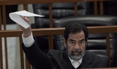 Saddam Hussein, holds up a piece of paper for the judge in court Monday Dec. 4, 2006 during his trial with other defendants in Baghdad, Iraq, for genocide in the 'Anfal' offensive against the Kurds. Saddam and six co-defendants, face possible execution if convicted for the 1987-88 military offensive against the Kurds of northern Iraq. The prosecution estimates that 180,000 Kurds were killed in the campaign, code-named Operation Anfal, in which Saddam's army allegedly destroyed hundreds of villages and killed or scattered their inhabitants. (AP 