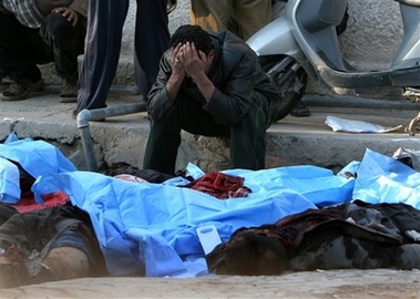 An Iraqi grieves over the bodies of his dead relatives at Al-Kindi hospital in Baghdad, Iraq, Tuesday, Dec. 12, 2006, following two synchronized explosions that occurred in Iraq's capital. Suspected insurgents set off two bombs in a main square of central Baghdad where scores of Iraqis were waiting for jobs as day laborers, killing at least 59 people and wounding 153, police said. (AP