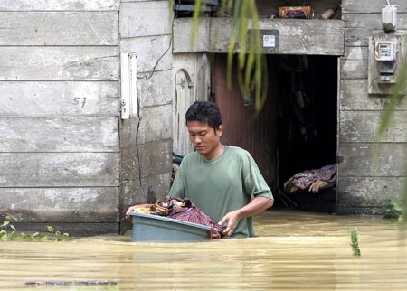 A man carries his belonging as he walks through floodwaters in front of his house in the district of Langkat in North Sumatra province December 24, 2006. Floods in Indonesia's Aceh and North Sumatra province have left at least 22 people dead and six missing, Health Ministry official Rustam Pakaya said on Sunday. 