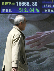 A pedestrian walks past a stock index board in Tokyo March 14, 2007. The Nikkei average was down 2.77 percent on Wednesday afternoon, led by exporters such as Honda Motor Co. Ltd., due to concerns about the U.S. economic outlook and a stronger yen. 