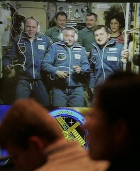 Officials and journalists watch a TV screen showing the crew aboard the ISS after the docking of a Soyuz space capsule with the International Space Station, in the Mission Control at Korolyov, just outside Moscow, Monday, April 9, 2007.