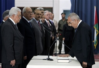 Palestinian President Mahmoud Abbas, left, looks at newly-appointed Palestinian Prime Minister Salam Fayad, placing his hand on the Quran, during a swearing in ceremony for the new government at Abbas headquarters in the West Bank town of Ramallah, Sunday, June 17, 2007. Abbas on Sunday swore in an emergency Cabinet, to replace the Hamas-Fatah coalition he dismantled after Hamas took control of Gaza by force. The Cabinet is led by respected economist Salam Fayyad, who will also serve as finance minister.