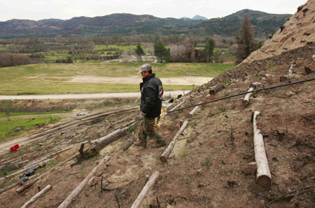 A worker carries a bag on a hill overlooking ancient Olympia's archaeological stadium February 11, 2208. Workers are racing against the clock to re-plant trees on ancient Olympia before next month's Beijing Games torch-lighting ceremony after the area was devastated by last year's forest fires. [Agencies]