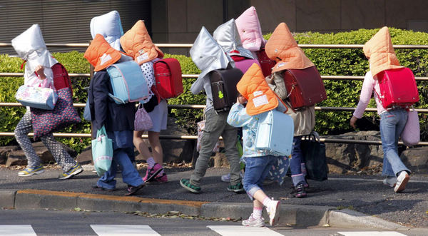 Elementary schoolchildren wear protective headgear as they walk to school in Tokyo April 25, 2011. Some schools in Tokyo have asked their students to wear the protective headgear on their way to school and while returning home since March 11's deadly earthquake and tsunami. Protective headgear for school children in Tokyo