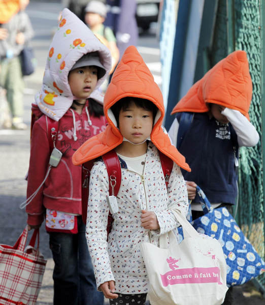 Elementary schoolchildren wear protective headgear as they walk to school in Tokyo April 25, 2011. Some schools in Tokyo have asked their students to wear the protective headgear on their way to school and while returning home since March 11's deadly earthquake and tsunami. Protective headgear for school children in Tokyo