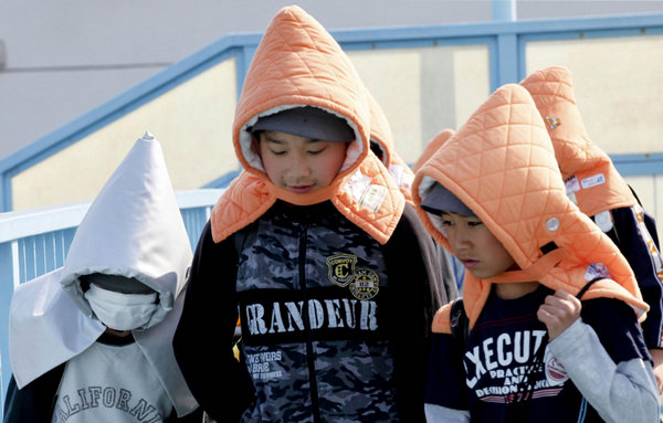 Elementary schoolchildren wear protective headgear as they walk to school in Tokyo April 25, 2011. Some schools in Tokyo have asked their students to wear the protective headgear on their way to school and while returning home since March 11's deadly earthquake and tsunami. Protective headgear for school children in Tokyo